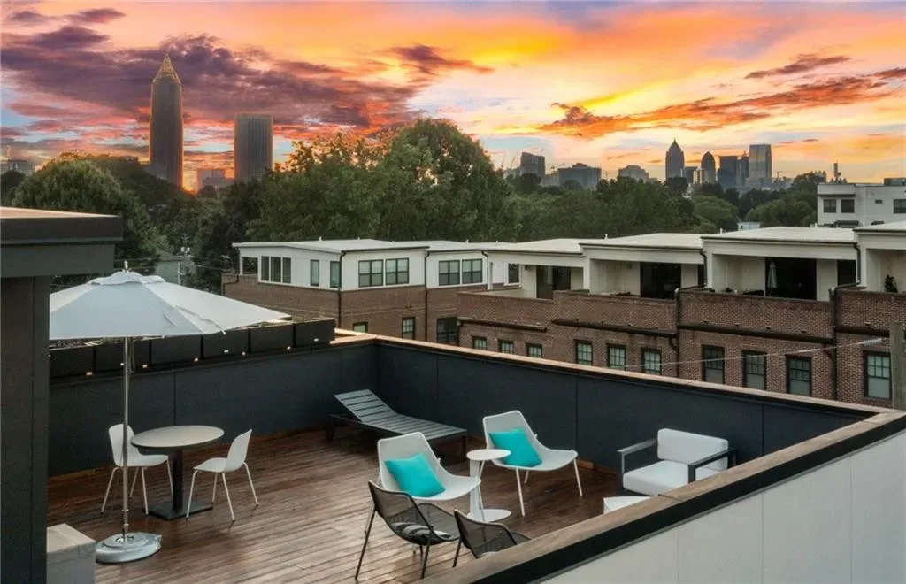 Rooftop terrace of the model townhome at sunset, lounge seating facing the glowing Midtown Atlanta skyline.